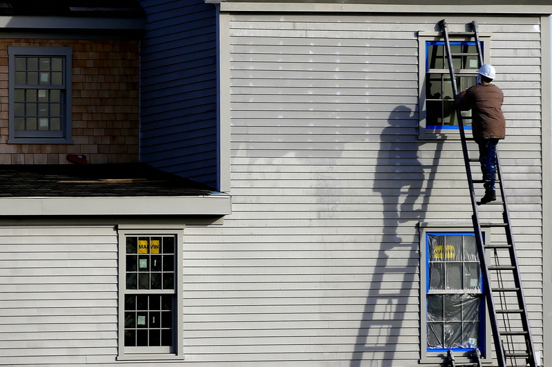 A man and his shadow prepare the windows for painting of a building being built in downtown New Bedford, MA. PHOTO PETER PEREIRA