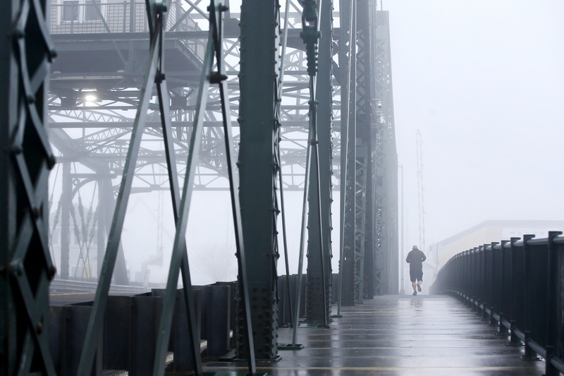 A man makes his way across the Fairhaven Bridge on a foggy morning jog in New Bedford, MA. PHOTO PETER PEREIRA