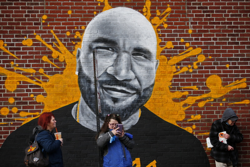 People waiting for the bus have big company in the mural of a man painting on a building on Pleasant Street in New Bedford, MA. PHOTO PETER PEREIRA