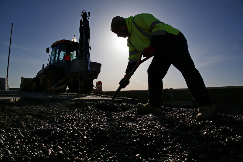 Fernando Conde of New Bedford DPI shovels gravel into a sink hole which was created after waves crashed into the side of a pier on East Beach due to a storm last week.  PHOTO PETER PEREIRA