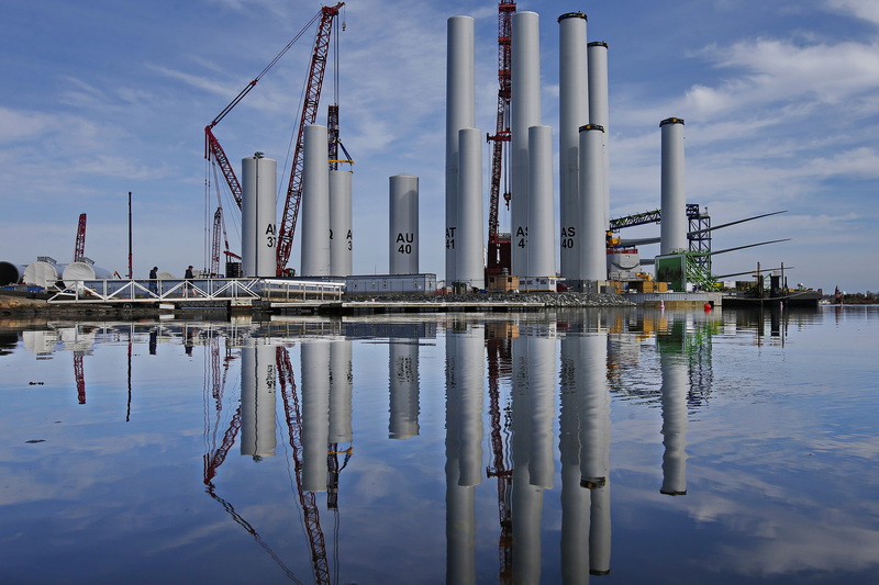 Two men walk across the bridge to the dock in front of the wind turbine towers for the Vineyard Wind offshore wind farm being assembled at the New Bedford Marine Commerce Terminal.  PHOTO PETER PEREIRA