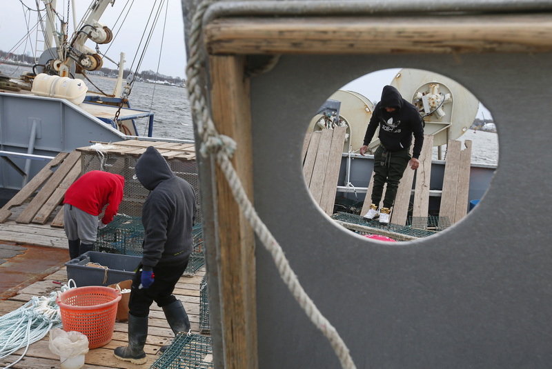 Fishermen aboard a lobster boat docked at State Pier in New Bedford, MA fix the traps before heading back out to sea. PHOTO PETER PEREIRA