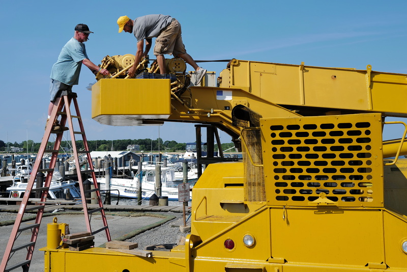 Jim Tripp, owner, and Steve Simonin work on repairing a crane at Davis & Tripp Marina in Dartmouth, MA. PHOTO PETER PEREIRA