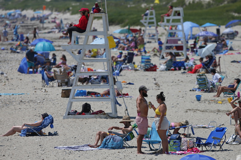 A woman sprays some sunscreen on a man at Horseneck Beach in Westport, MA as temperatures continue to rise across the Northeast. PHOTO PETER PEREIRA