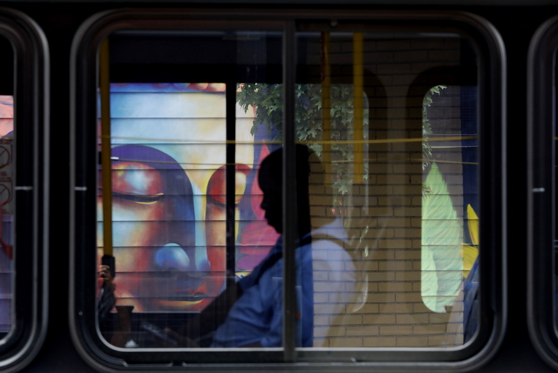 A man rides the bus as it makes its way past the mural of a Buddah painted on the side of the Spicy Lime building in downtown New Bedford, MA. PHOTO PETER PEREIRA