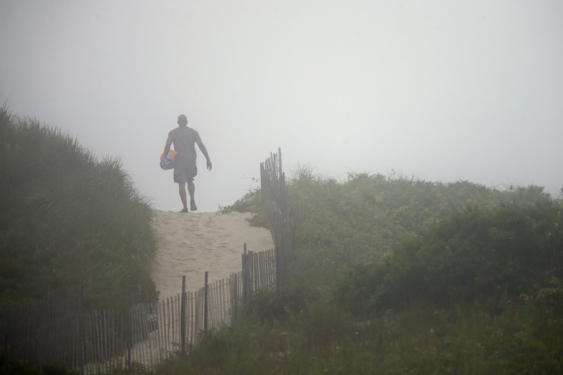 A man crests a dune as he makes his way to Horseneck Beach on a foggy morning in Westport, MA. PHOTO PETER PEREIRA