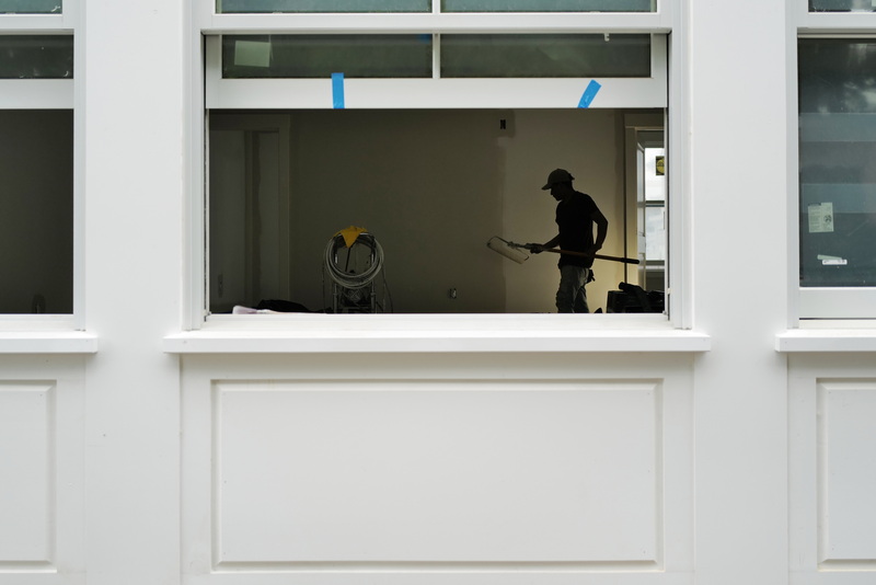 A painter puts a fresh coat of paint on the wall as seen through the window of a new set of businesses being constructed on Elm Street in South Dartmouth, MA.  PHOTO PETER PEREIRA