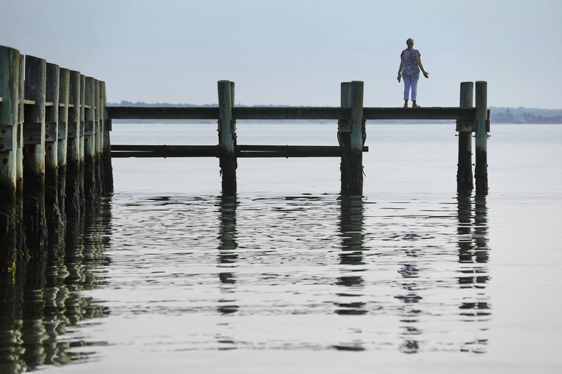 Bernadette Souza stands on a dock in the south end of New Bedford, MA with head pointed up and arms open.  When asked, Bernadette responded 'I was offering a prayer for all of the world