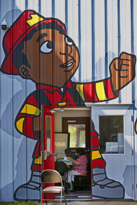 Literacy Director, Saralee Salk, is seen teaching English to a Vietnamese man in one of the ESL classes as see through the open door with a fireman painted outside at the Dennison Memorial Community Center on 1st Street in New Bedford, MA.  PHOTO PETER PEREIRA