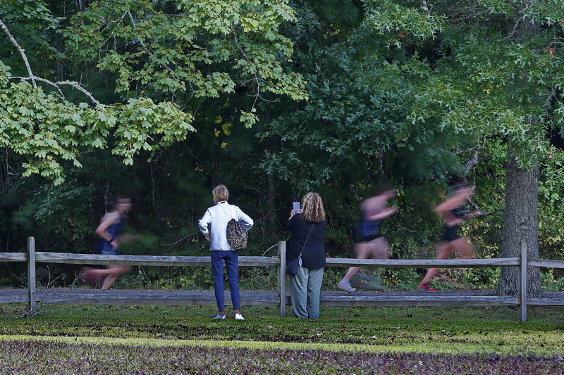 Two women look on as runners speed by at the Apponequet versus ORR cross country meet at Washburn Park in Marion, MA. PHOTO PETER PEREIRA