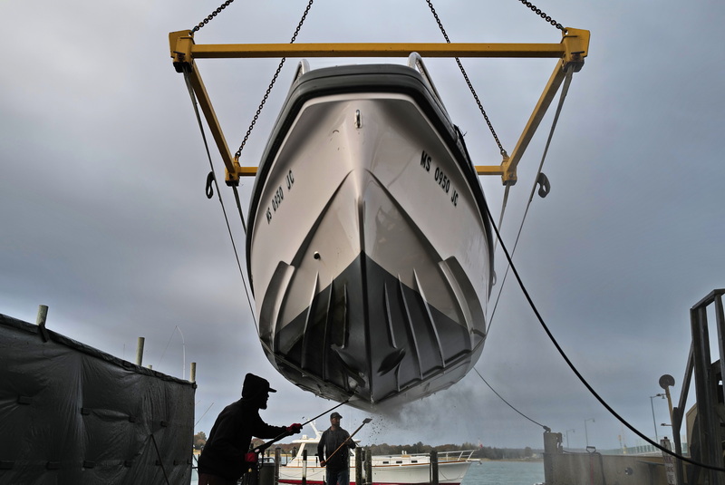 Chad Richard and Steve Simonin clean the hull of a power boat they just removed from the water at Davis & Tripp in Dartmouth, MA. PHOTO PETER PEREIRA