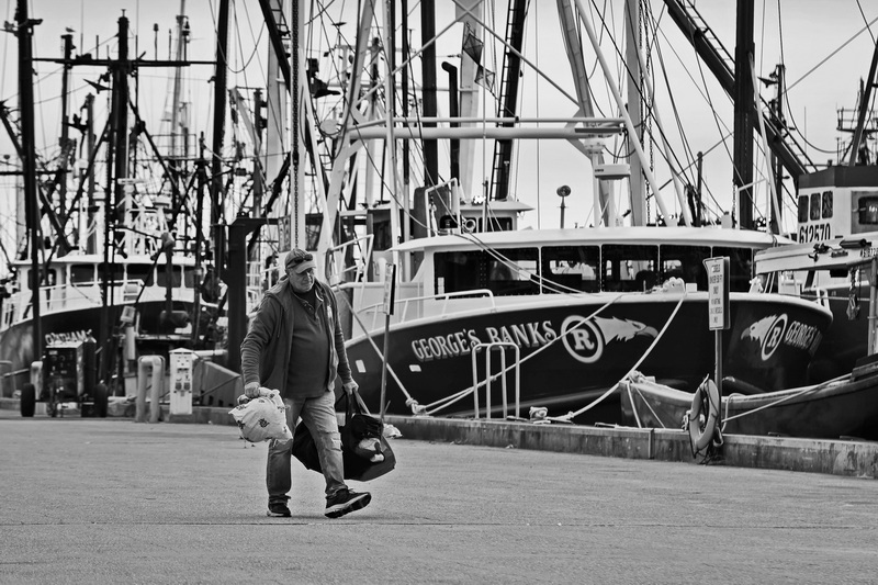 Carrying two bags with his personal belongings, Bruce Medeiros, heads back to his car in New Bedford, MA after arriving from a five-day fishing voyage aboard the lobster boat, Fishing Addiction. PHOTO PETER PEREIRA