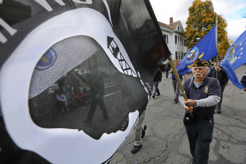 Through the POW flag a member of the VFW 6643 is seen as he fellow veterans march down Union Street during the 2024 New Bedford, MA Veterans Day parade. PHOTO PETER PEREIRA