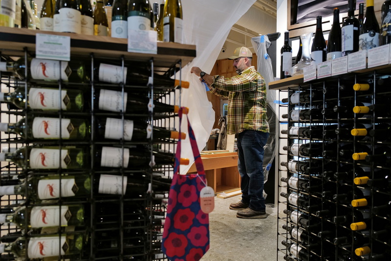 Jeff Isidoro, R.P. Valois Construction supervisor, installs a temporary barrier in front of the wine section of Farm & Coast in Dartmouth, MA as construction on an updated wine section proceeds in the background. PHOTO PETER PEREIRA
