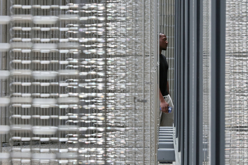 A UMass Dartmouth student walks into the Claire T. Carney Library past the metal link panels adorning the exterior of the building in Dartmouth, MA. PHOTO PETER PEREIRA