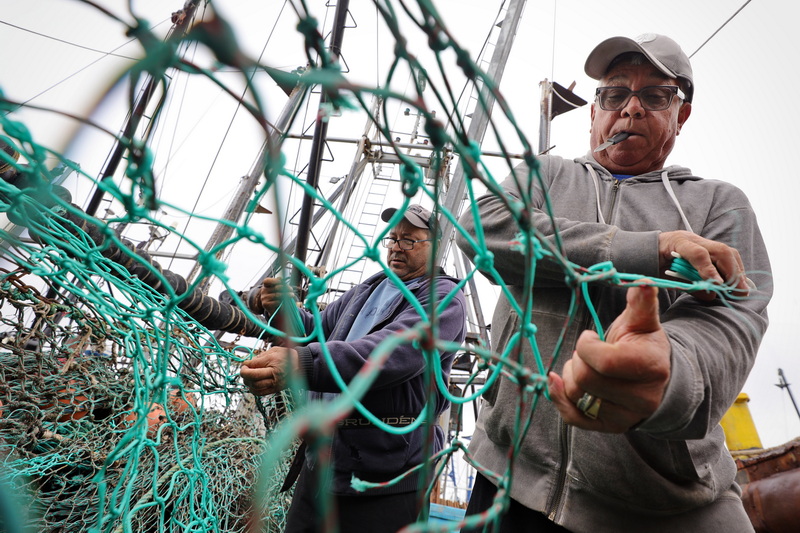 Fishermen aboard the Seel Jr. fishing boat docked in New Bedford, MA make repairs to the groundfishing net, before heading back out to sea. PHOTO PETER PEREIRA