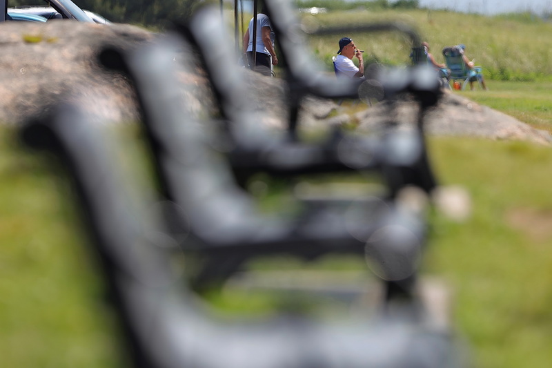 A man smokes a cigar while looking out into Buzzards Bay from Fort Phoenix in Fairhaven, MA as seen through the gap in the benches facing the water. PHOTO PETER PEREIRA