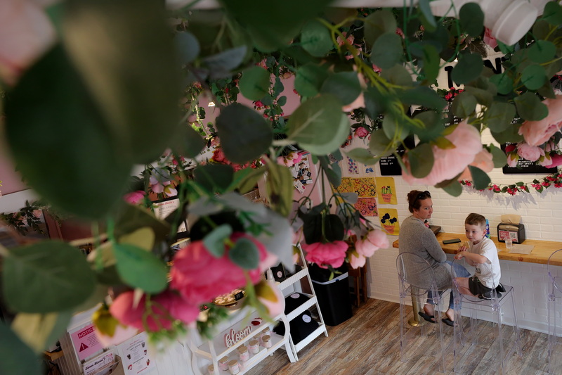 Flower decorations hang from the ceiling as Bridget Bourque and her son Andr� Bourque enjoys a sugar cookie in the shape of a number two, celebrating Sweet Lizzie's Bake Shop's second anniversary since opening on Main Street in Fairhaven, MA. PHOTO PETER PEREIRA