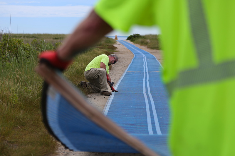 Fairhaven Highway Department workmen install a beach mat on the path leading to the beach on West Island in Fairhaven, MA. PHOTO PETER PEREIRA