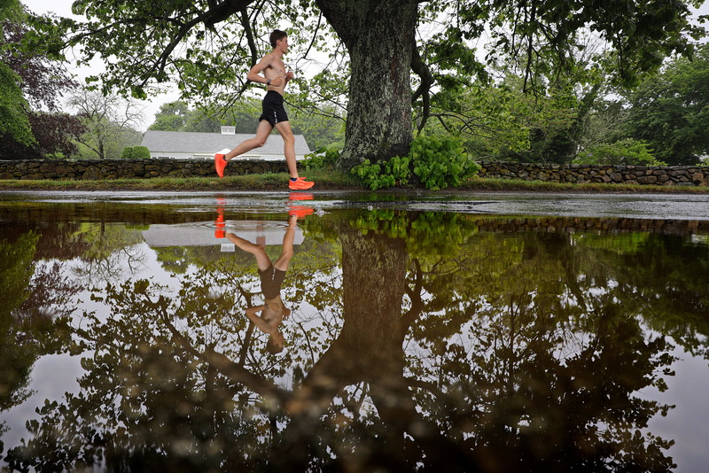 On a rainy morning in Mattapoisett, MA, following a night of heavy rain, a man�s reflection appears in a large puddle as he runs along the fittingly named Water Street. PHOTO PETER PEREIRA