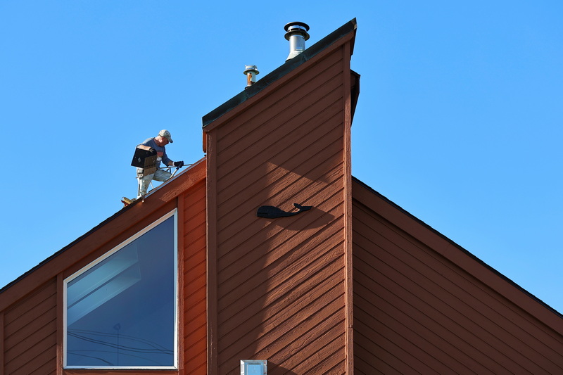 On October 7, 2026, a roofer removes shingles from a house in New Bedford, MA that features a whale decoration, before putting in a new roof on the sloped surface. PHOTO PETER PEREIRA