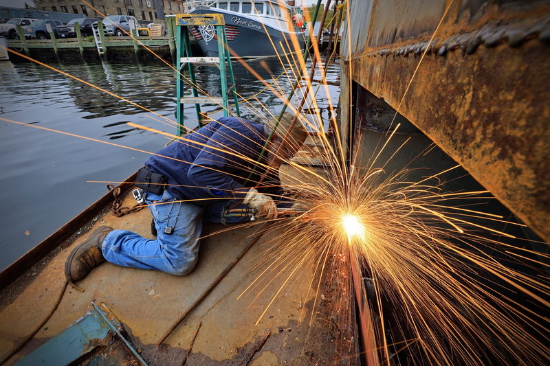 Sparks fly as Winston Reyes, of Blue Fleet Welding, cuts a rusted panel from the side of a fishing boat he is repairing in New Bedford, MA, on October 13, 2026. PHOTO PETER PEREIRA