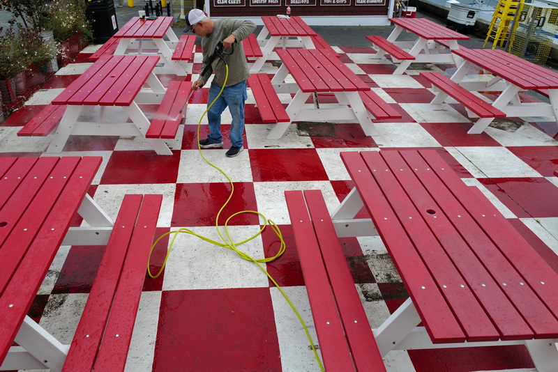 A man uses a powerwasher to clean the colorful picnic tables at the Whale's Tail Clam Bar in New Bedford, MA on October 14, 2026, before storing them for the winter. PHOTO PETER PEREIRA