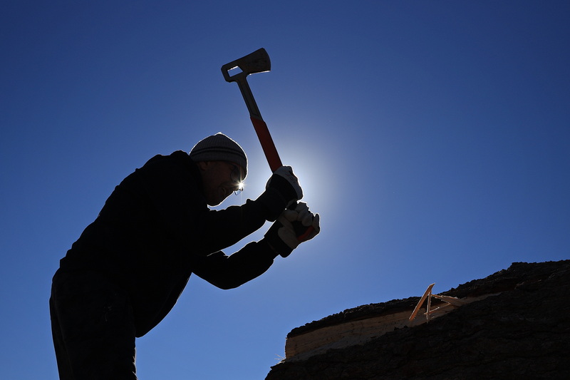 On October 19, 2026, Mashpee Wompanoag tribe member Harman Deetz uses an axe to strip bark from the tree trunk he plans to shape into a mishoon canoe at the Community Boating Center in New Bedford, MA. PHOTO PETER PEREIRA