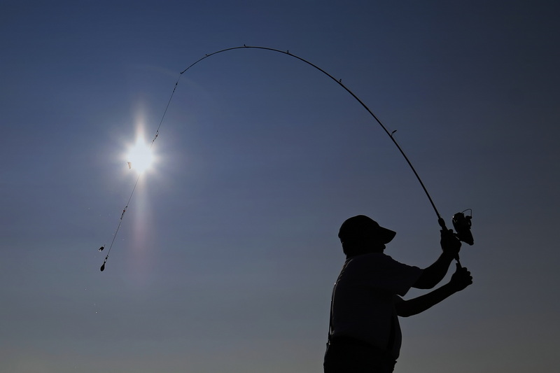 A man seemingly casts the early morning sun as he fished from the wharf in Mattapoisett, MA.  PHOTO PETER PEREIRA