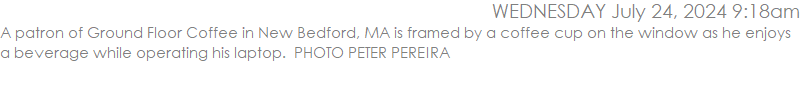 A patron of Ground Floor Coffee in New Bedford, MA is framed by a coffee cup on the window as he enjoys a beverage while operating his laptop.  PHOTO PETER PEREIRA