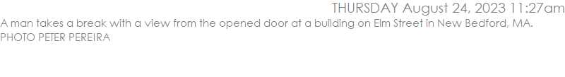 A man takes a break with a view from the opened door at a building on Elm Street in New Bedford, MA.  PHOTO PETER PEREIRA