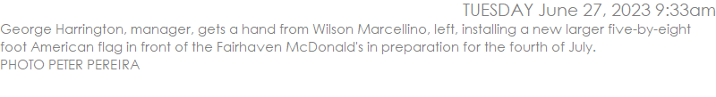George Harrington, manager, gets a hand from Wilson Marcellino, left, installing a new larger five-by-eight foot American flag in front of the Fairhaven McDonald's in preparation for the fourth of July. PHOTO PETER PEREIRA